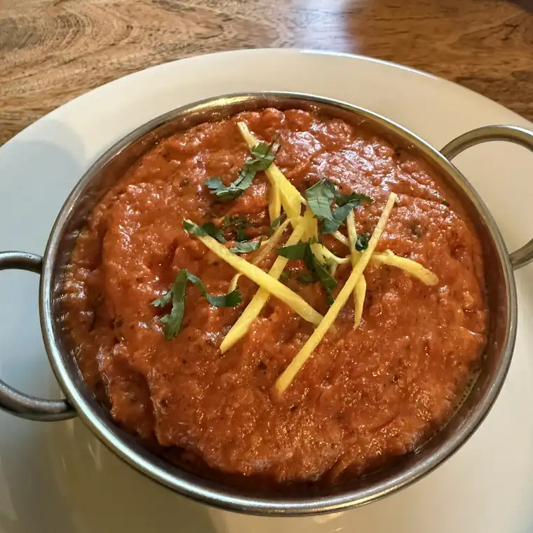 Curry w metalowej misce z paskami imbiru i kolendrą