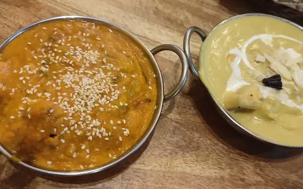 Dwa curry w metalowych miseczkach na stole